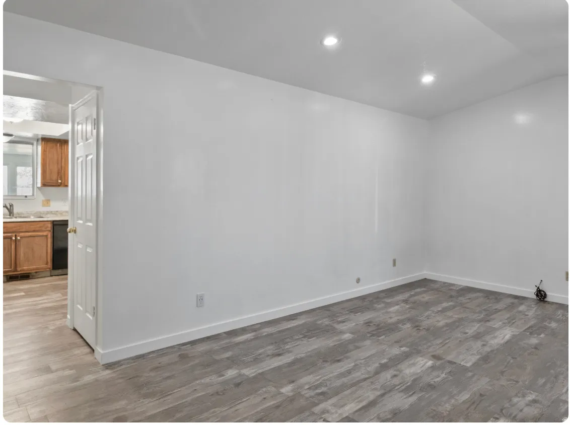 Recessed ceiling lighting, wood-finish flooring, white walls, and a solid core interior door