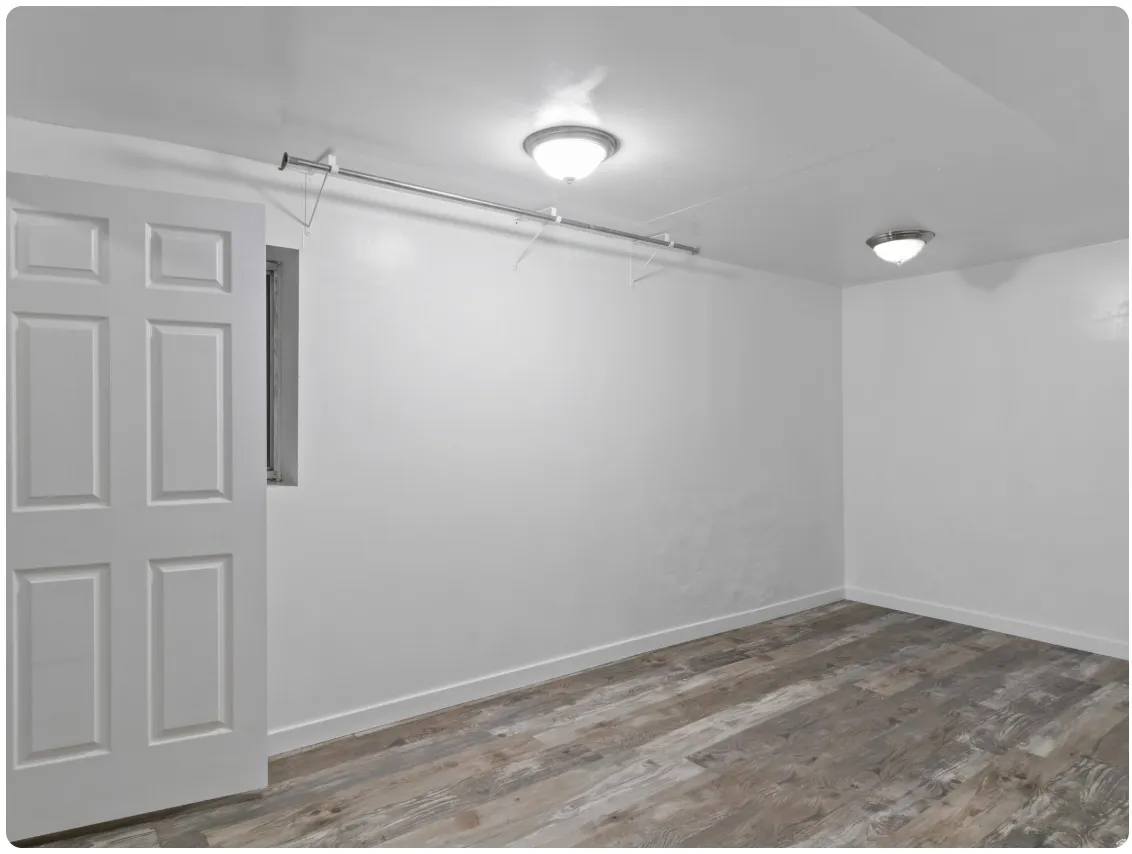 Recessed window, white paneled door, wood-finish flooring, two flush-mount ceiling lights, and integrated storage rod