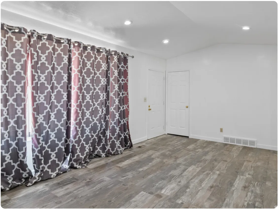 Vaulted ceiling with recessed lighting, wood-finish flooring, and white interior doors