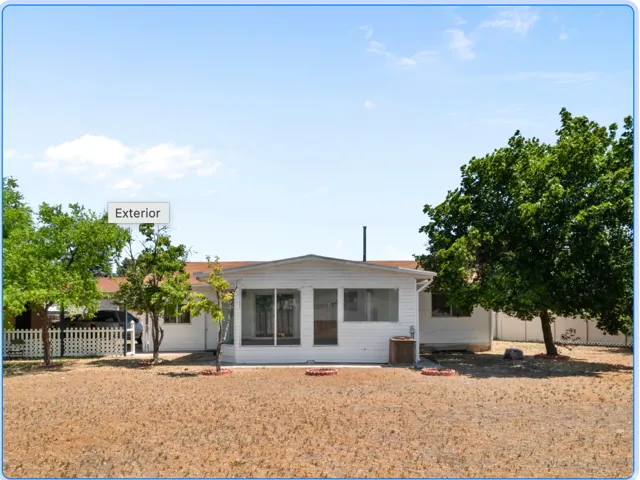 White exterior with a screened-in porch, covered carport, and mature trees