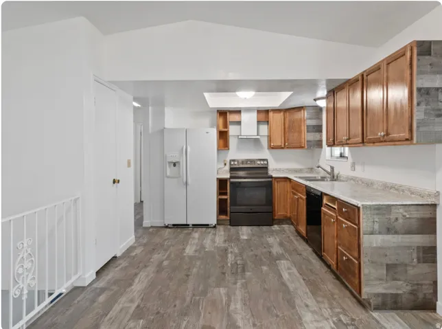 Kitchen featuring wood-finish flooring, wood cabinetry, stone-finish countertops, and a full suite of appliances