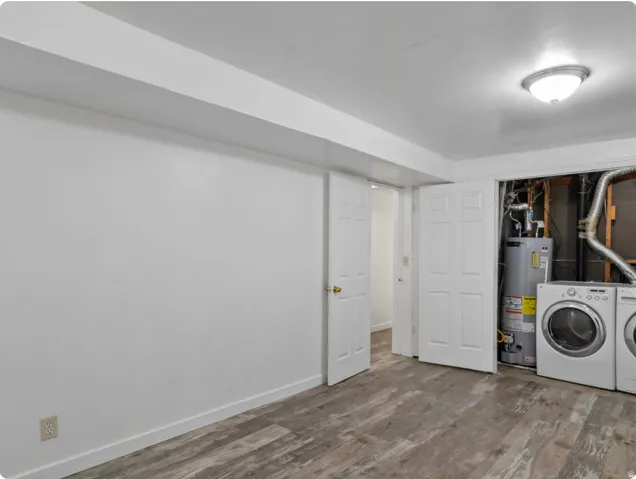 Wood-finish flooring, white paneled doors, ceiling-mounted light fixture, and laundry appliances