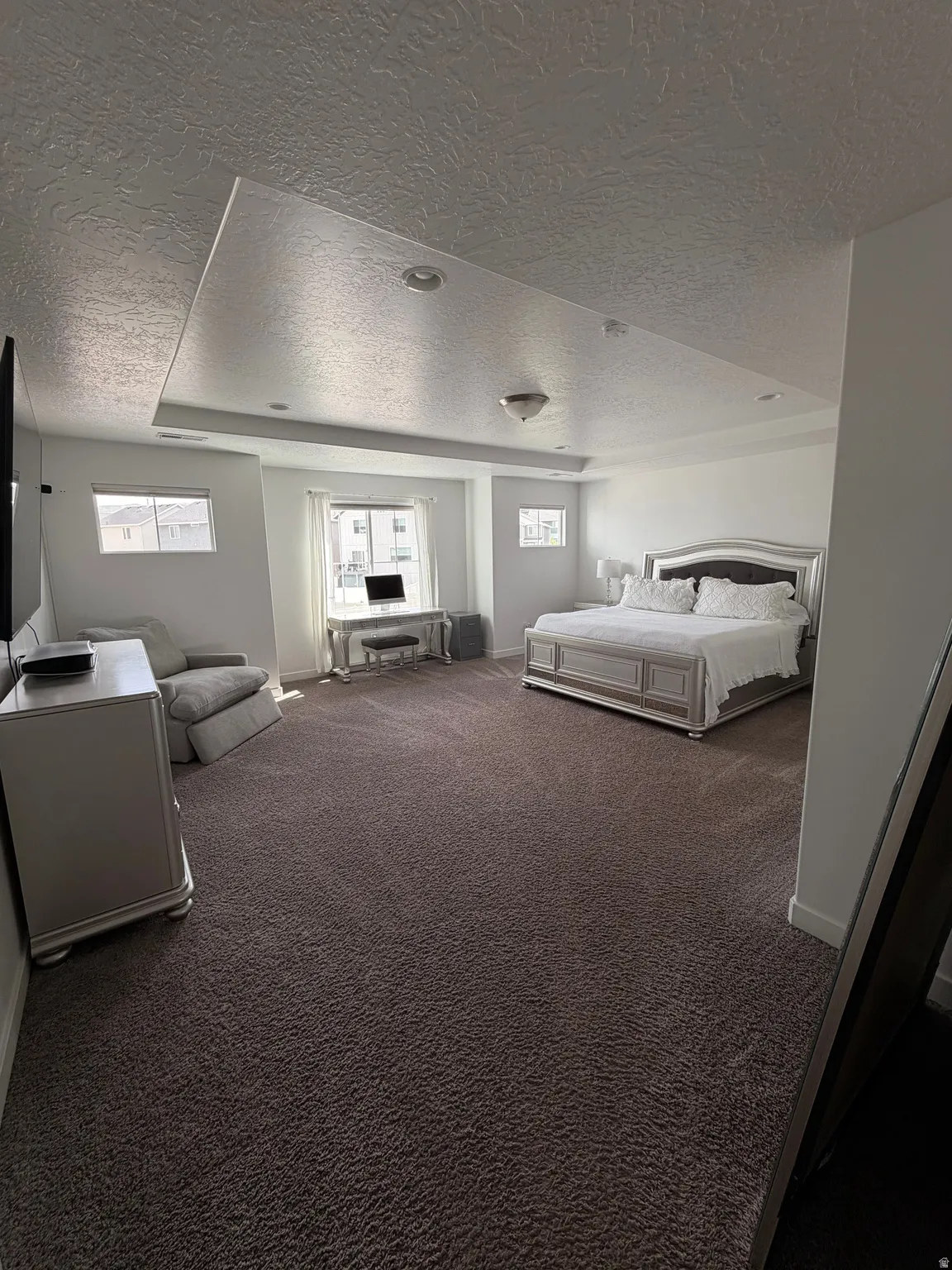 Recessed lighting and a tray ceiling complement a neutral color palette