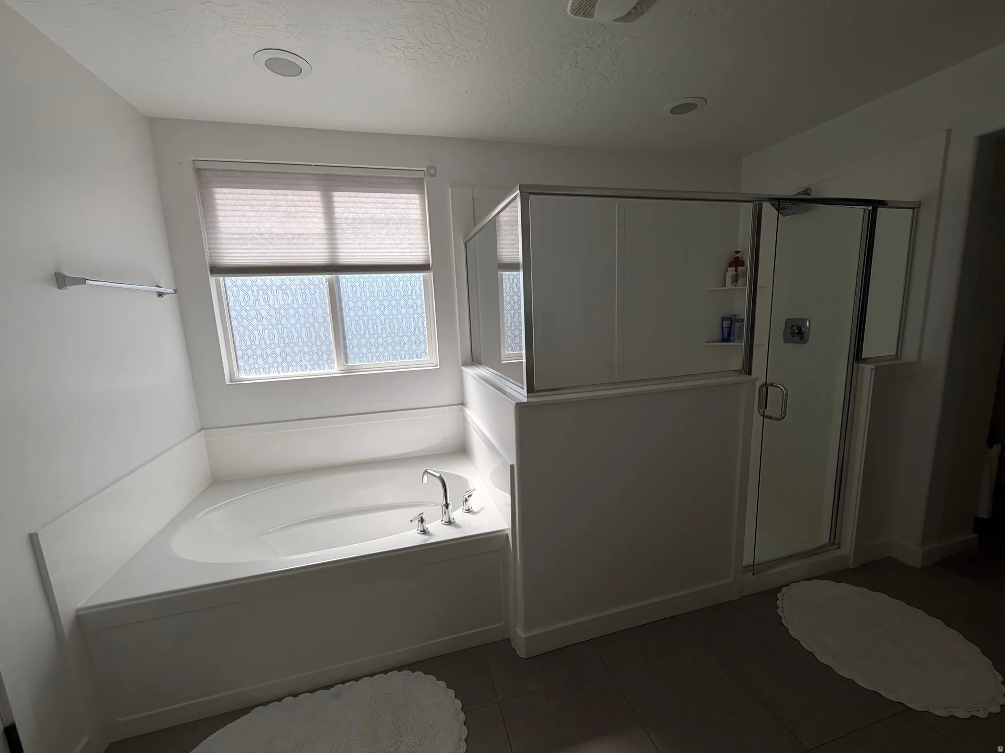 Built-in soaking tub with chrome fixtures, frosted privacy window, and an adjacent glass-enclosed shower