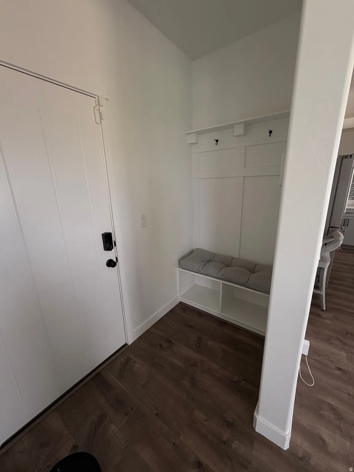 Entryway featuring wood-finish flooring, a built-in bench with integrated shelving, and wall-mounted hooks