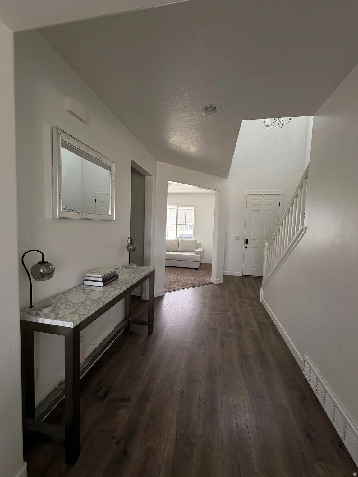 Wood-finish flooring, white wall paint, recessed ceiling light, white painted staircase, and a white paneled entry door