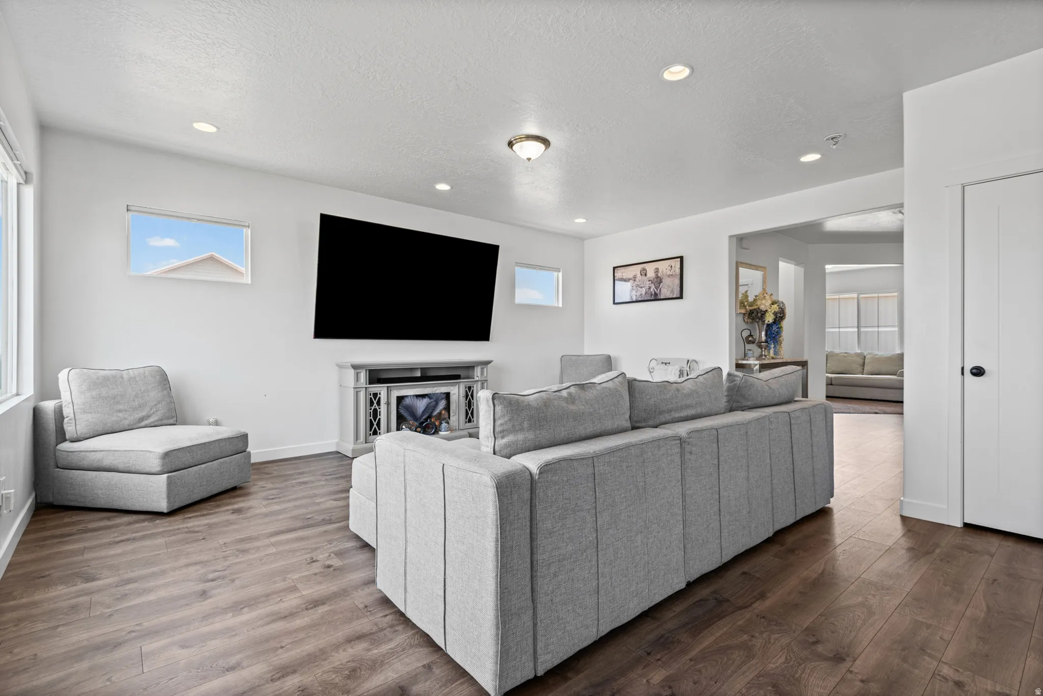 Recessed lighting, wood-finish flooring, white walls, and a built-in media console