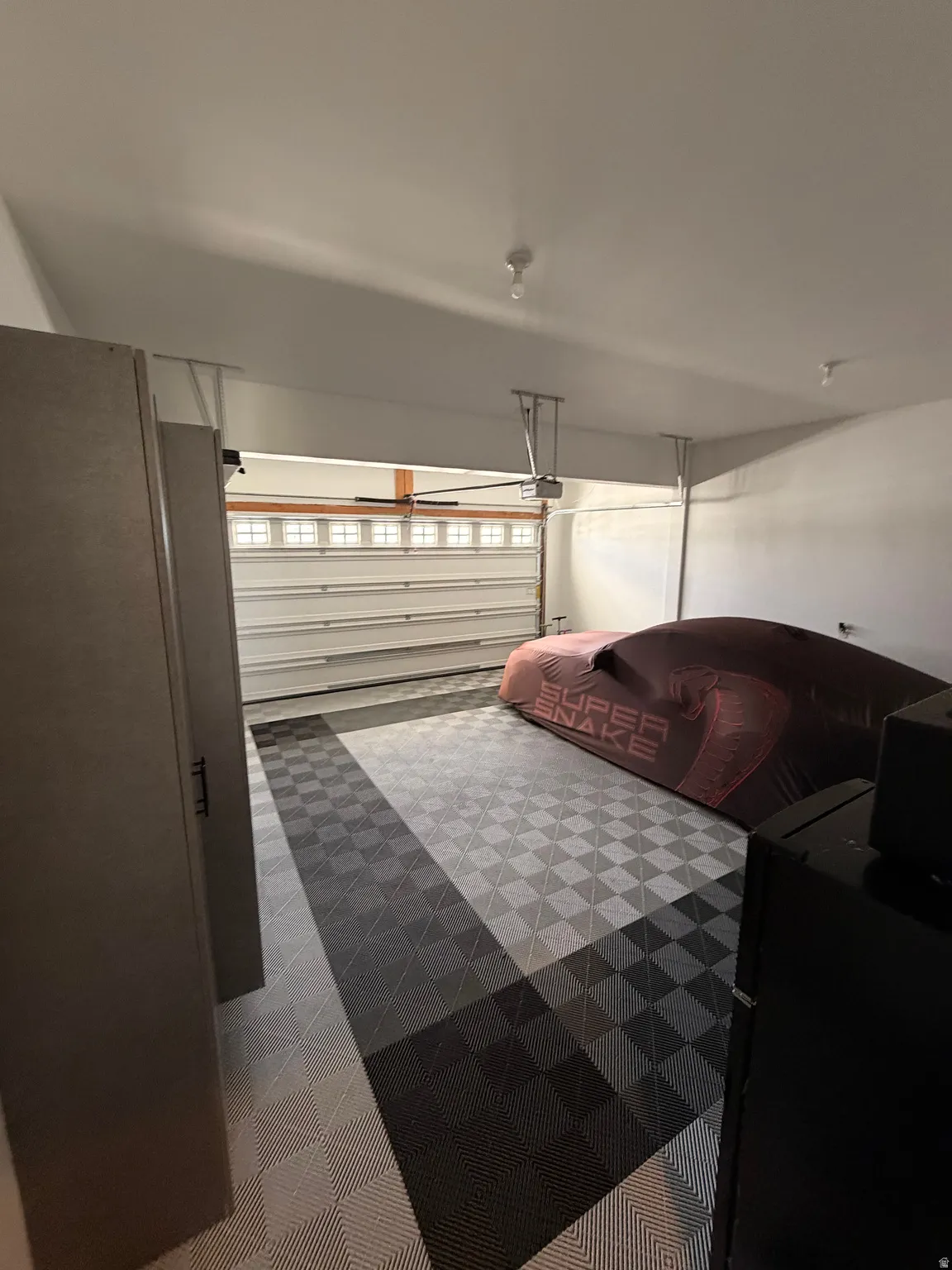 Garage featuring checkerboard pattern flooring and overhead lighting
