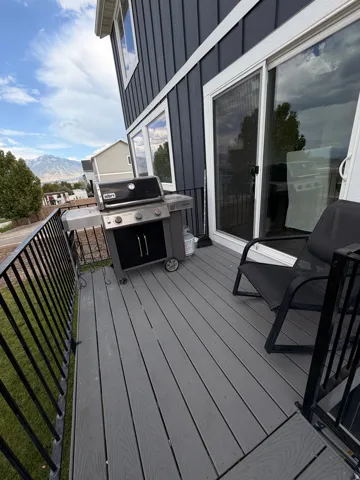 Composite deck with black metal railing, sliding glass door access, and dark vertical siding