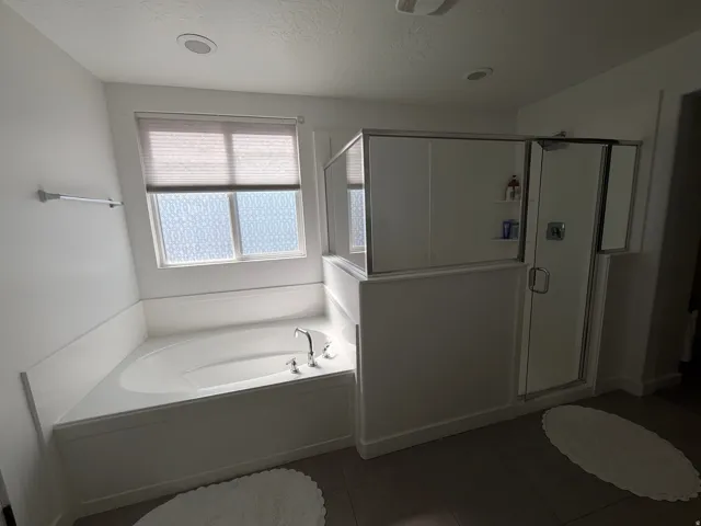 Built-in soaking tub with chrome fixtures, frosted privacy window, and an adjacent glass-enclosed shower