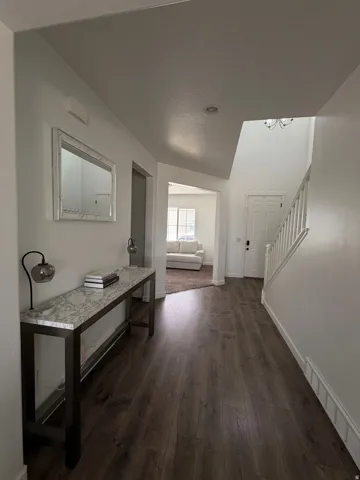 Wood-finish flooring, white wall paint, recessed ceiling light, white painted staircase, and a white paneled entry door