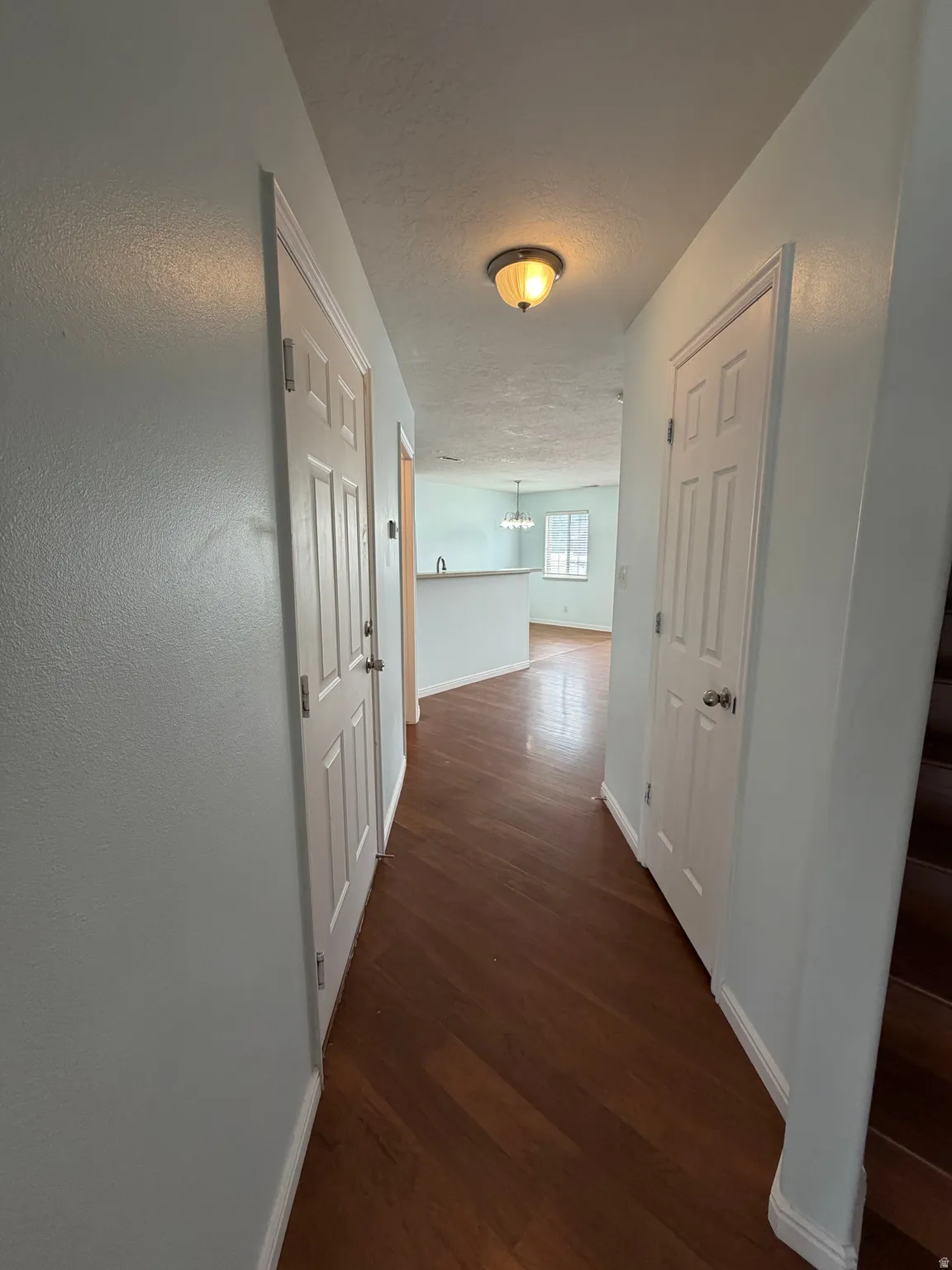 Wood-finish flooring throughout, light-colored walls, recessed lighting fixture, paneled doors, and a built-in half-wall