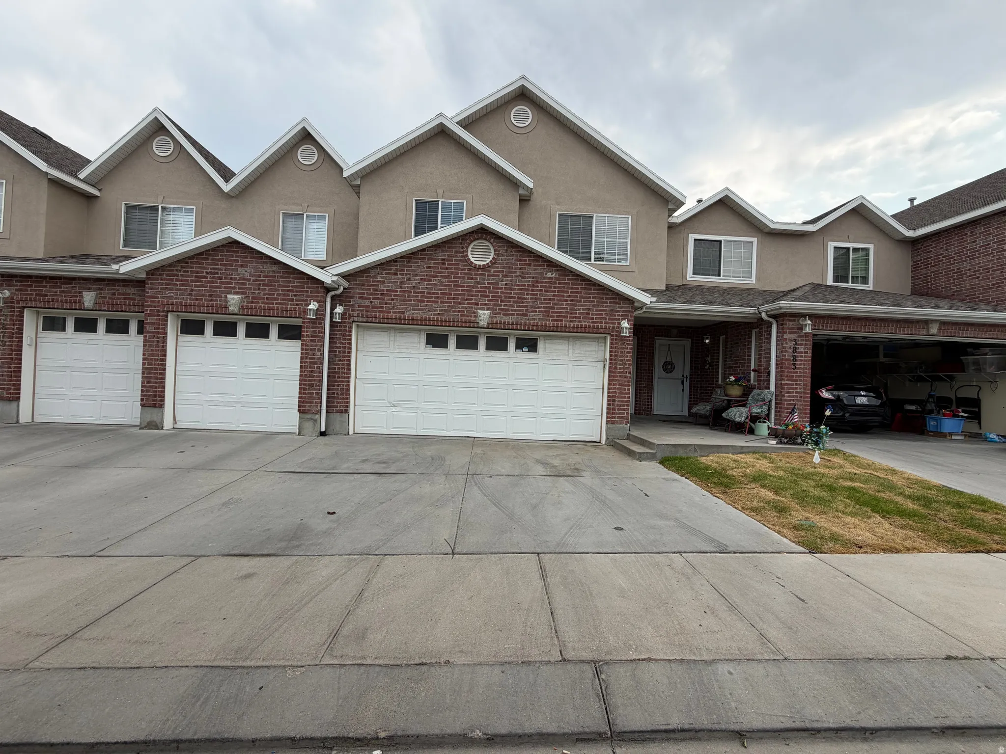 Brick and stucco exterior with multiple gabled rooflines, white garage doors, and individual driveways