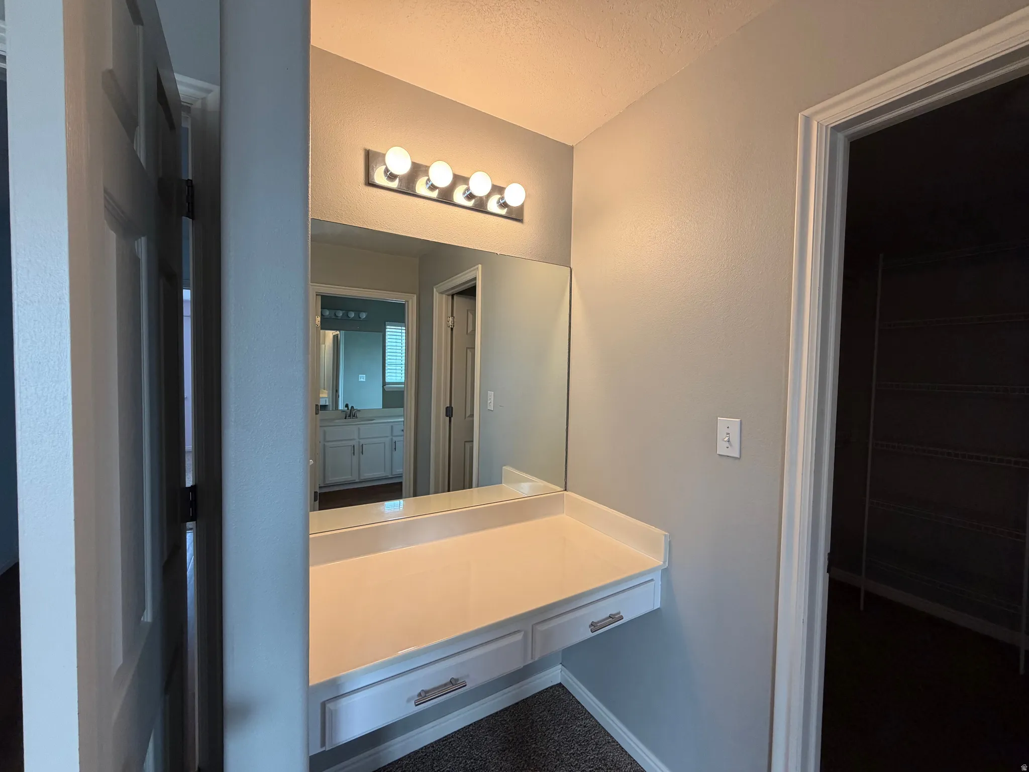 Built-in vanity with integrated countertop, wall-mounted mirror, and overhead lighting fixture