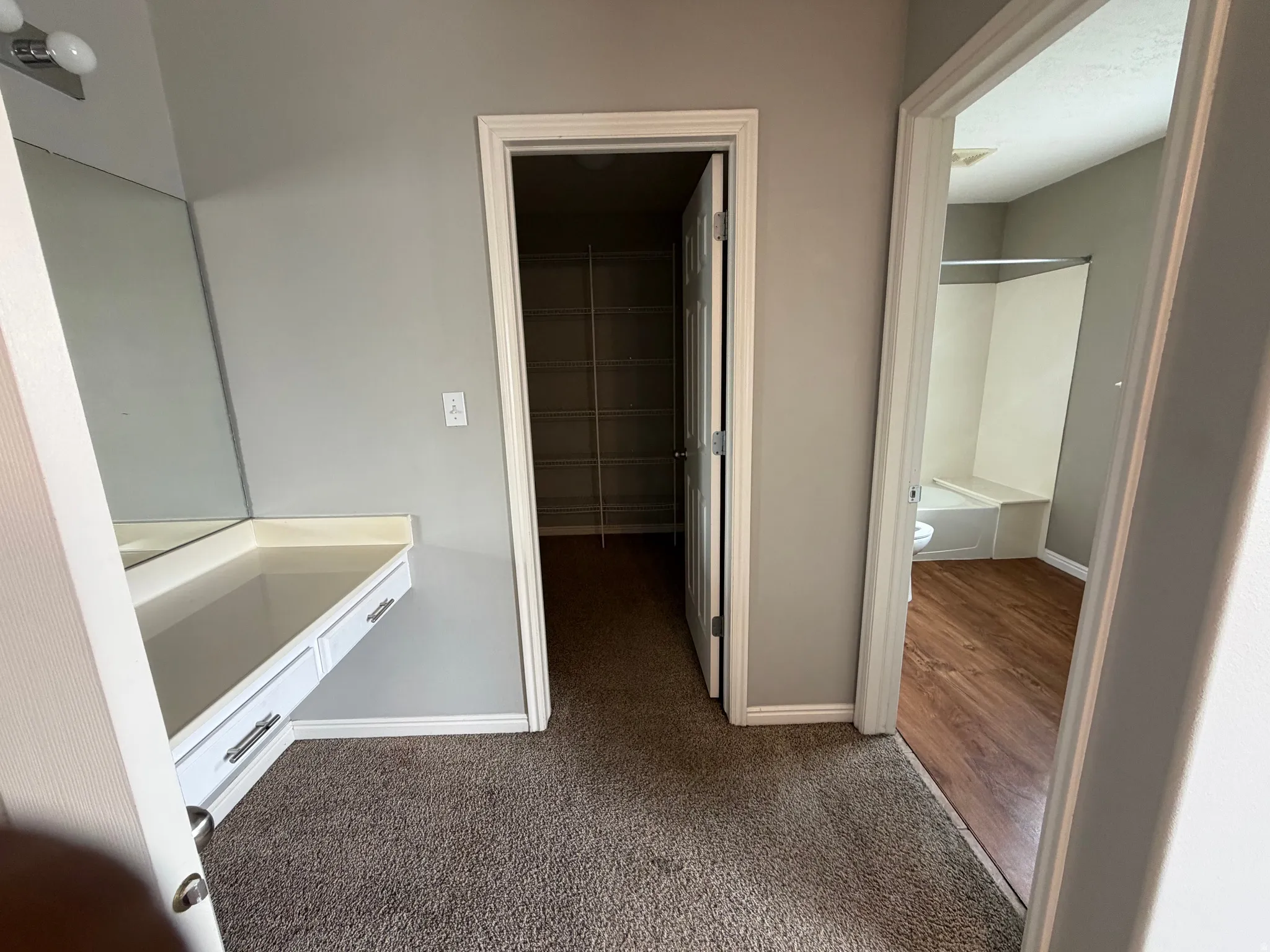 Built-in vanity with mirror, white cabinetry, and polished hardware