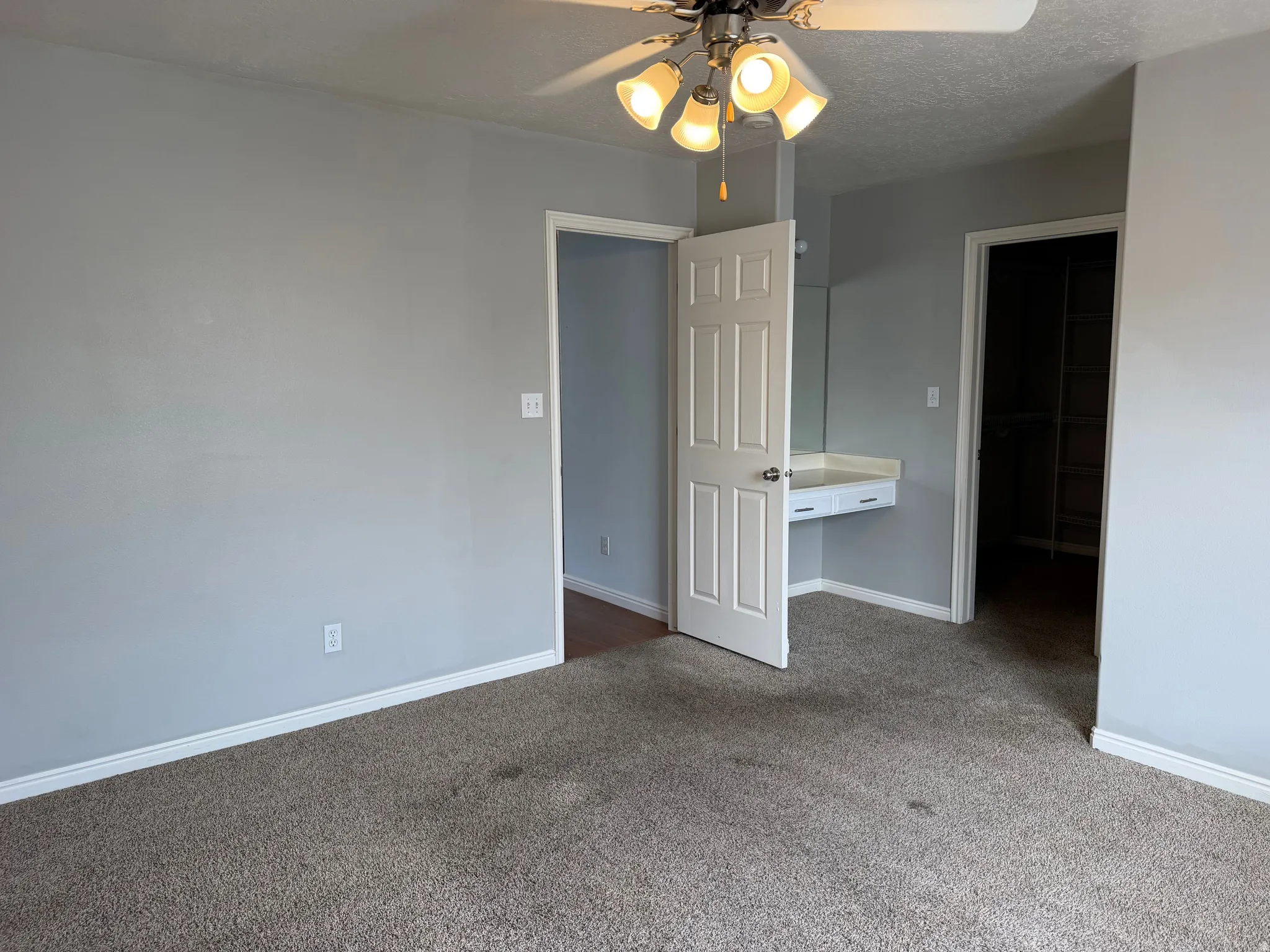 Recessed built-in vanity with mirror, overhead ceiling fan with light fixture, carpet flooring, and painted interior walls
