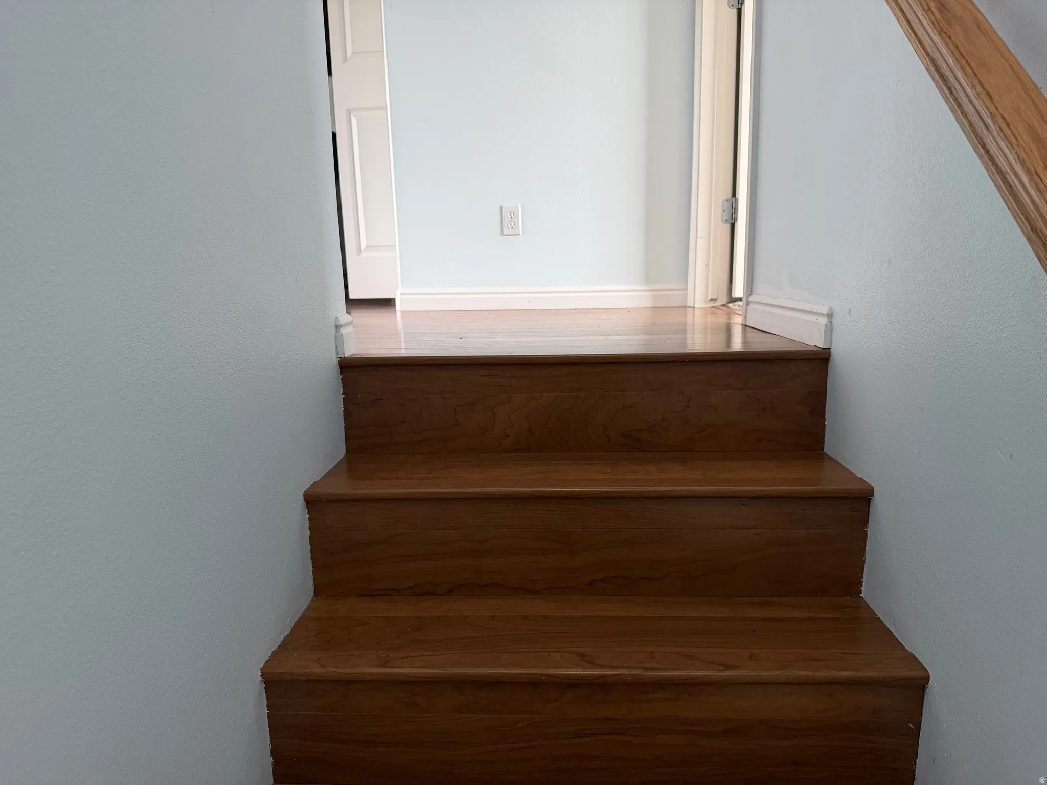 Wood-finish staircase with light-toned wall paint and white trim details