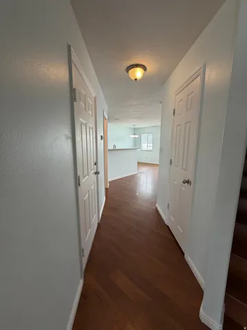Wood-finish flooring throughout, light-colored walls, recessed lighting fixture, paneled doors, and a built-in half-wall