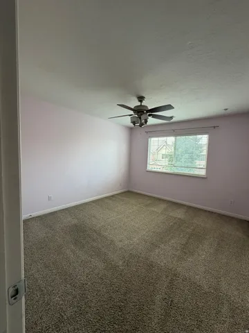 Textured carpeting, window with blinds, overhead ceiling fan with lighting, and light-colored wall paint