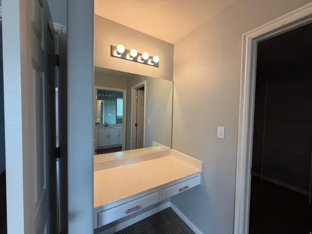 Built-in vanity with integrated countertop, wall-mounted mirror, and overhead lighting fixture