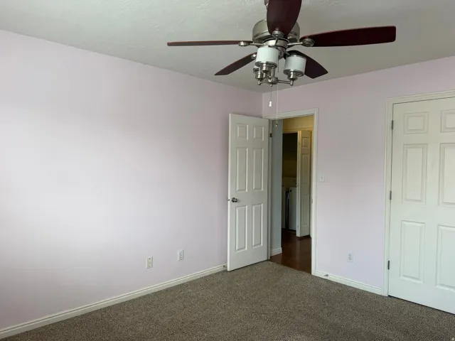 Carpeted flooring, ceiling fan with integrated lighting, two panel doors, and light-toned wall finishes