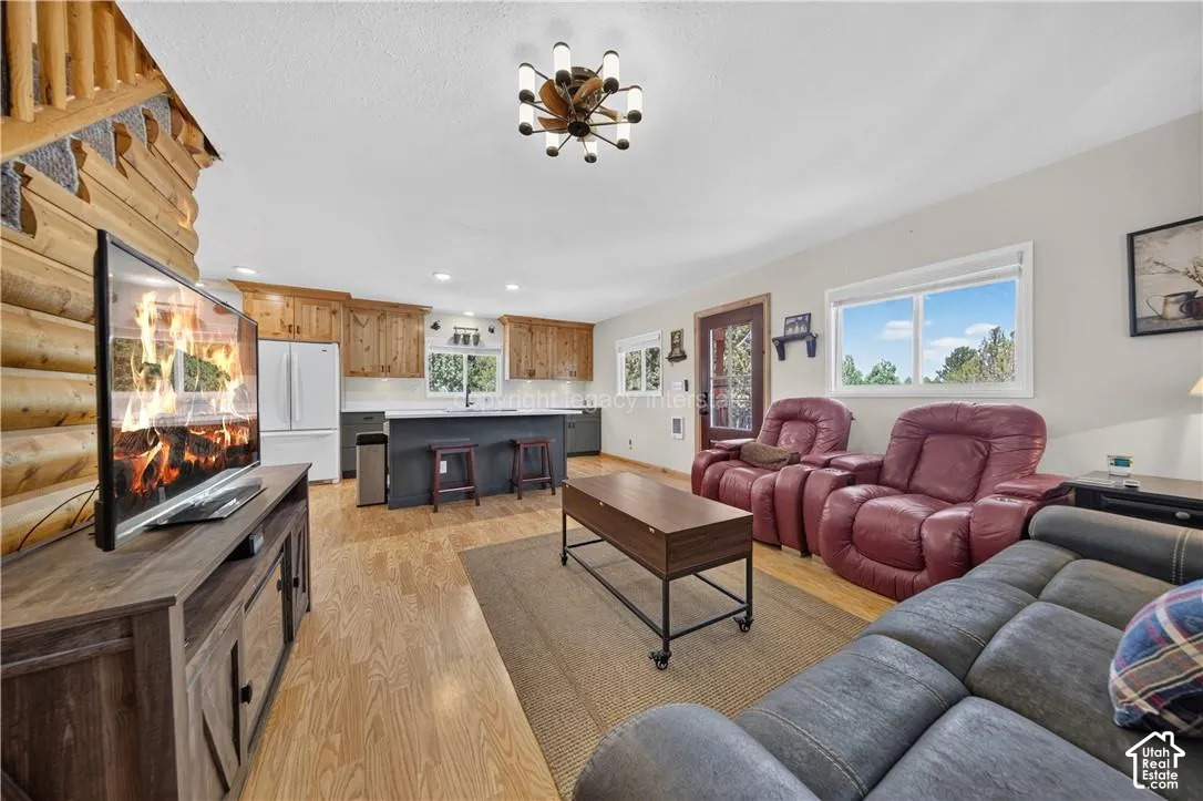 Open-concept living area featuring a log wall, wood-finish flooring, and a kitchen with wood cabinetry