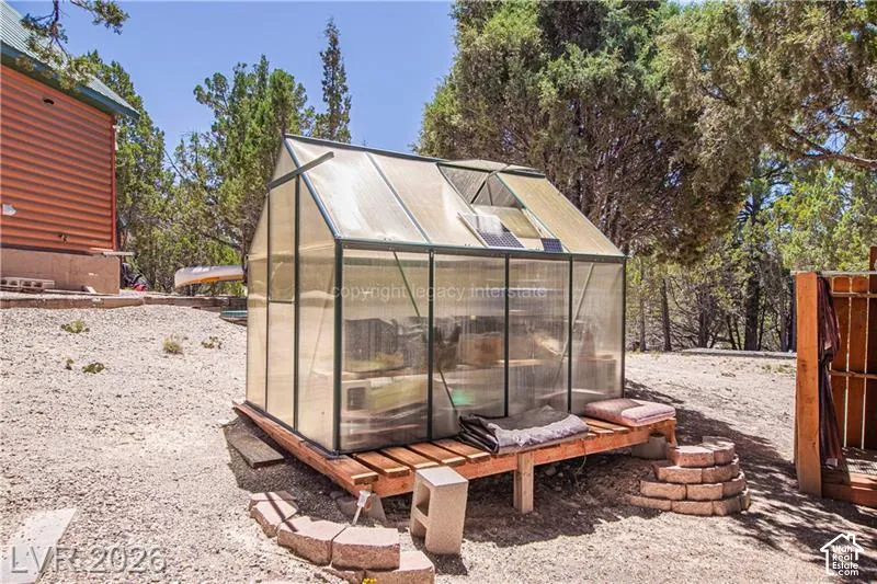 Freestanding greenhouse with an automatic roof vent, solar panel, and wood platform base