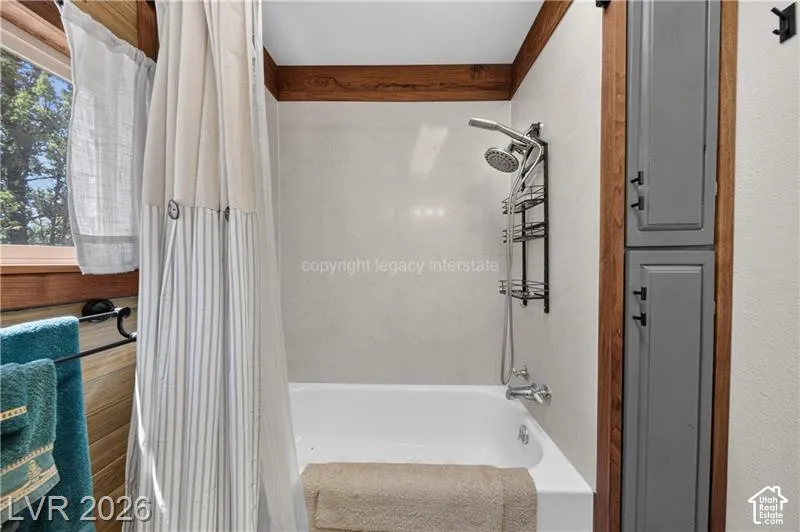 Bathtub with a wall-mounted shower system, complemented by full-height built-in cabinetry with matte black hardware