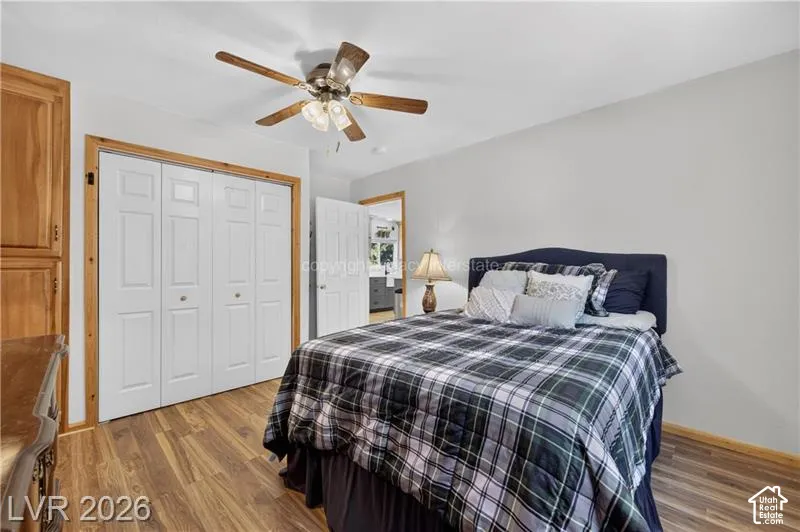 Wood-finish flooring, ceiling fan with integrated lighting, built-in bi-fold closet doors, and wood-finish trim