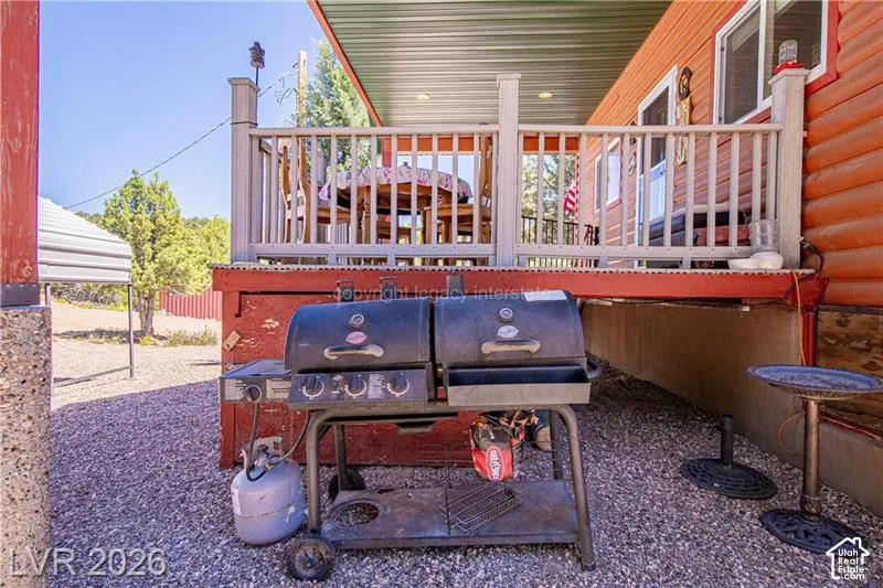 Exterior featuring a covered patio, railing, and rough-hewn wood siding