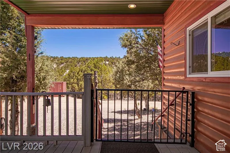 Covered porch with exposed wood beams, recessed lighting, and a composite deck surface