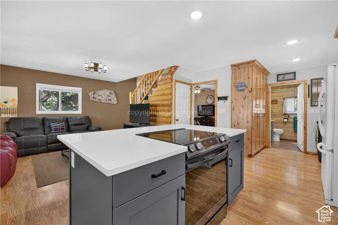 Kitchen island with a built-in range, white countertop, and dark cabinetry