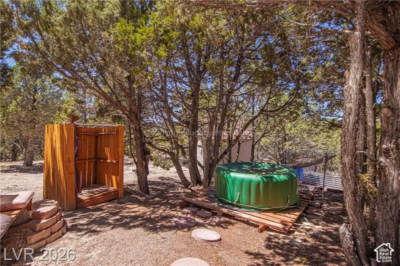 Outdoor shower structure, circular stone hardscaping, lush surrounding trees