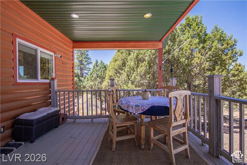 Covered outdoor deck with wood-finish siding, recessed lighting, and wooden railings