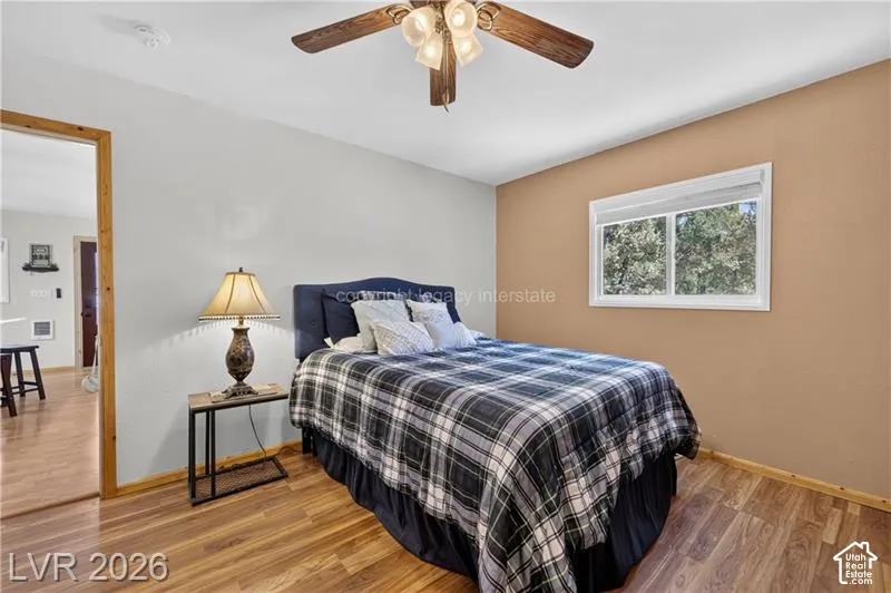 Wood-finish flooring, ceiling fan with integrated lighting, and a window offering natural illumination