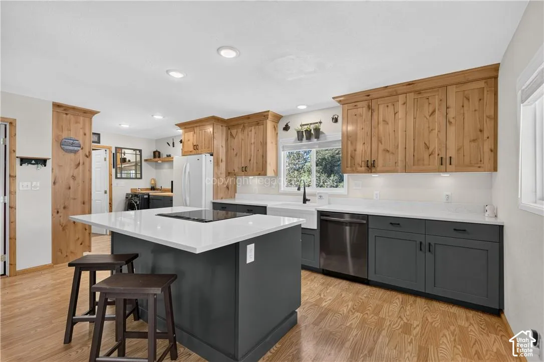 Wood-finish flooring throughout, complemented by a central island with a white countertop and integrated cooktop
