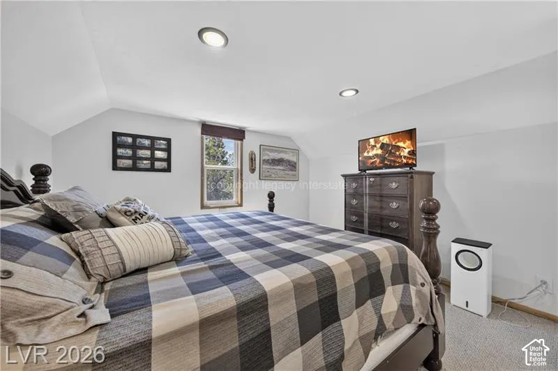 Recessed ceiling lighting illuminates the space, featuring sloped ceilings and a window with a wood frame