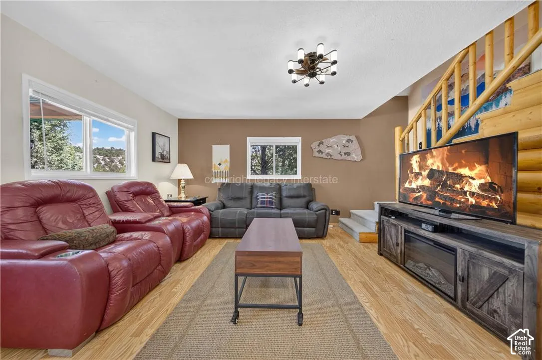 Wood-finish flooring with an area rug, natural wood staircase, and a contemporary ceiling light fixture