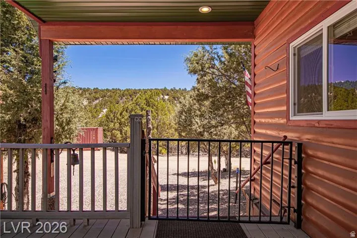 Covered porch with exposed wood beams, recessed lighting, and a composite deck surface