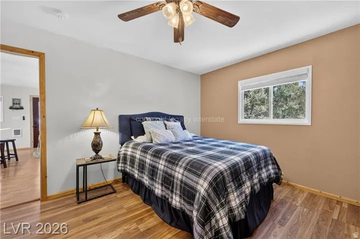 Wood-finish flooring, ceiling fan with integrated lighting, and a window offering natural illumination