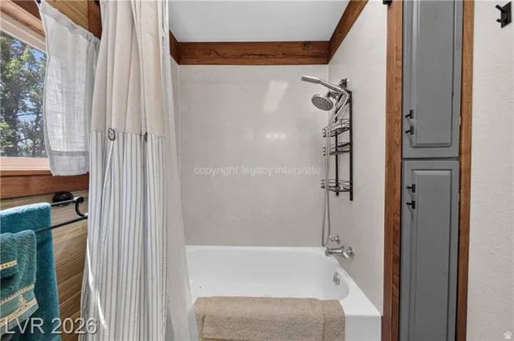 Bathtub with a wall-mounted shower system, complemented by full-height built-in cabinetry with matte black hardware