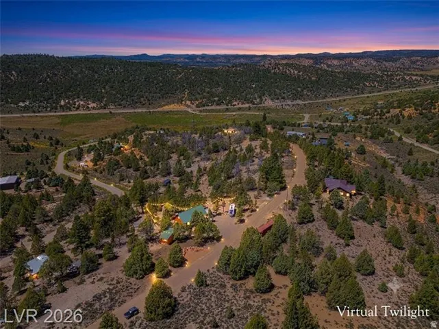 Expansive elevated property with multiple structures and winding driveways, surrounded by extensive natural landscaping