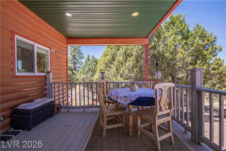 Covered outdoor deck with wood-finish siding, recessed lighting, and wooden railings