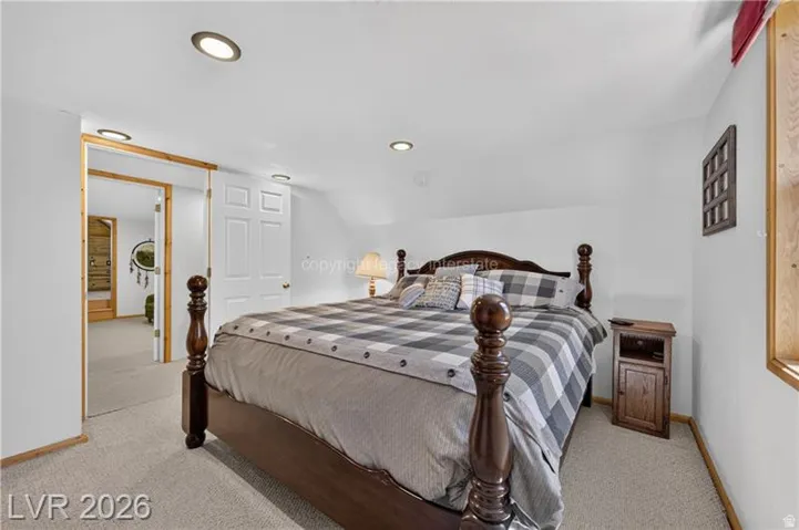 Recessed ceiling lighting, white walls, wood-trimmed doorway, and light-toned carpeting