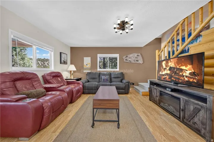 Wood-finish flooring with an area rug, natural wood staircase, and a contemporary ceiling light fixture
