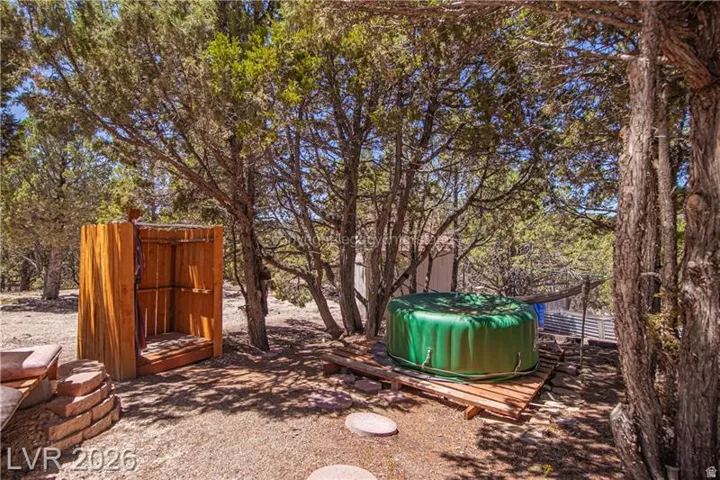 Outdoor shower structure, circular stone hardscaping, lush surrounding trees