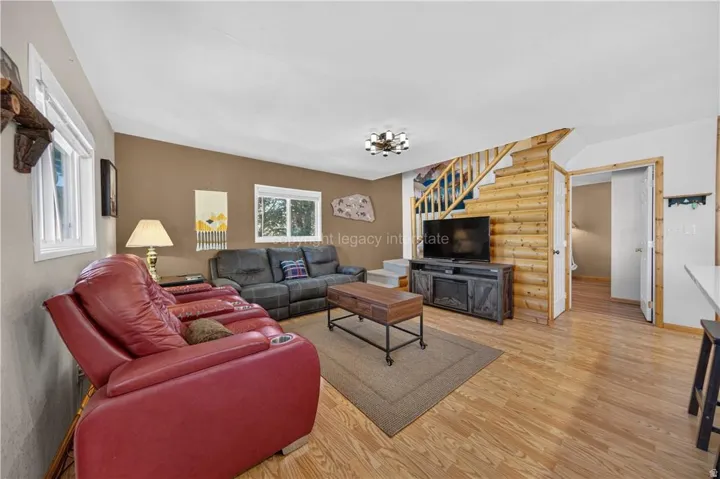 Wood-finish flooring throughout, light neutral walls, and a built-in log wall feature