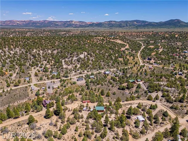 Expansive land parcel with surrounding terrain, mountainous backdrop, and established dirt roads