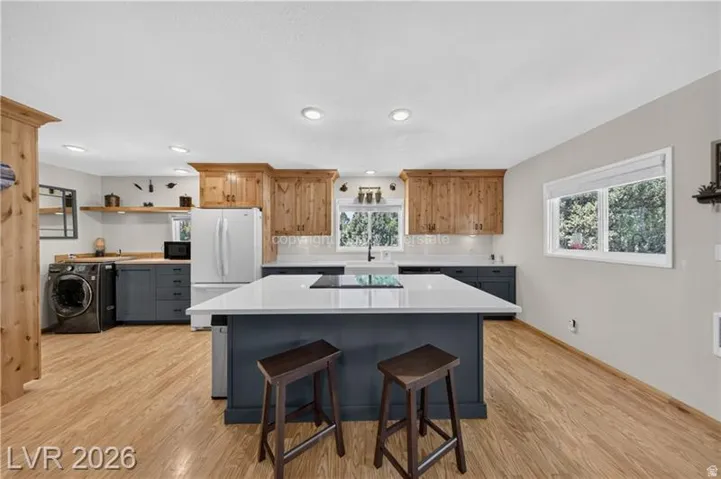 Spacious kitchen featuring an expansive island, wood-finish flooring, two-tone cabinetry, recessed lighting, and white countertops