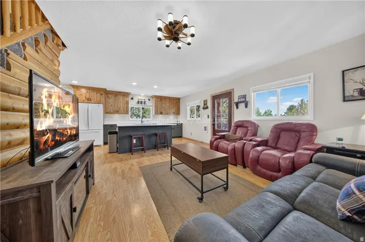 Open-concept living area featuring a log wall, wood-finish flooring, and a kitchen with wood cabinetry